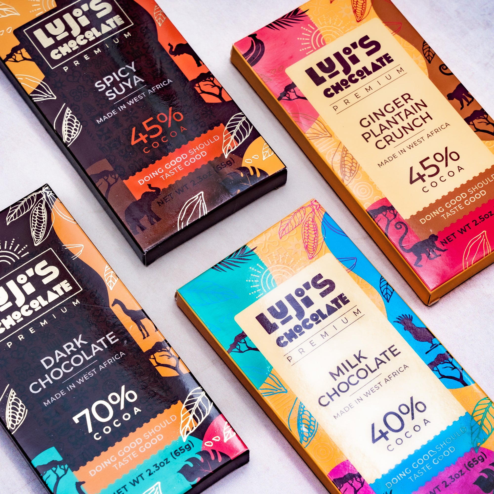 A fanned display of Luji's Chocolate bars in various flavors, each with its unique wrapper design featuring bright colors and African animal silhouettes, against a dark background